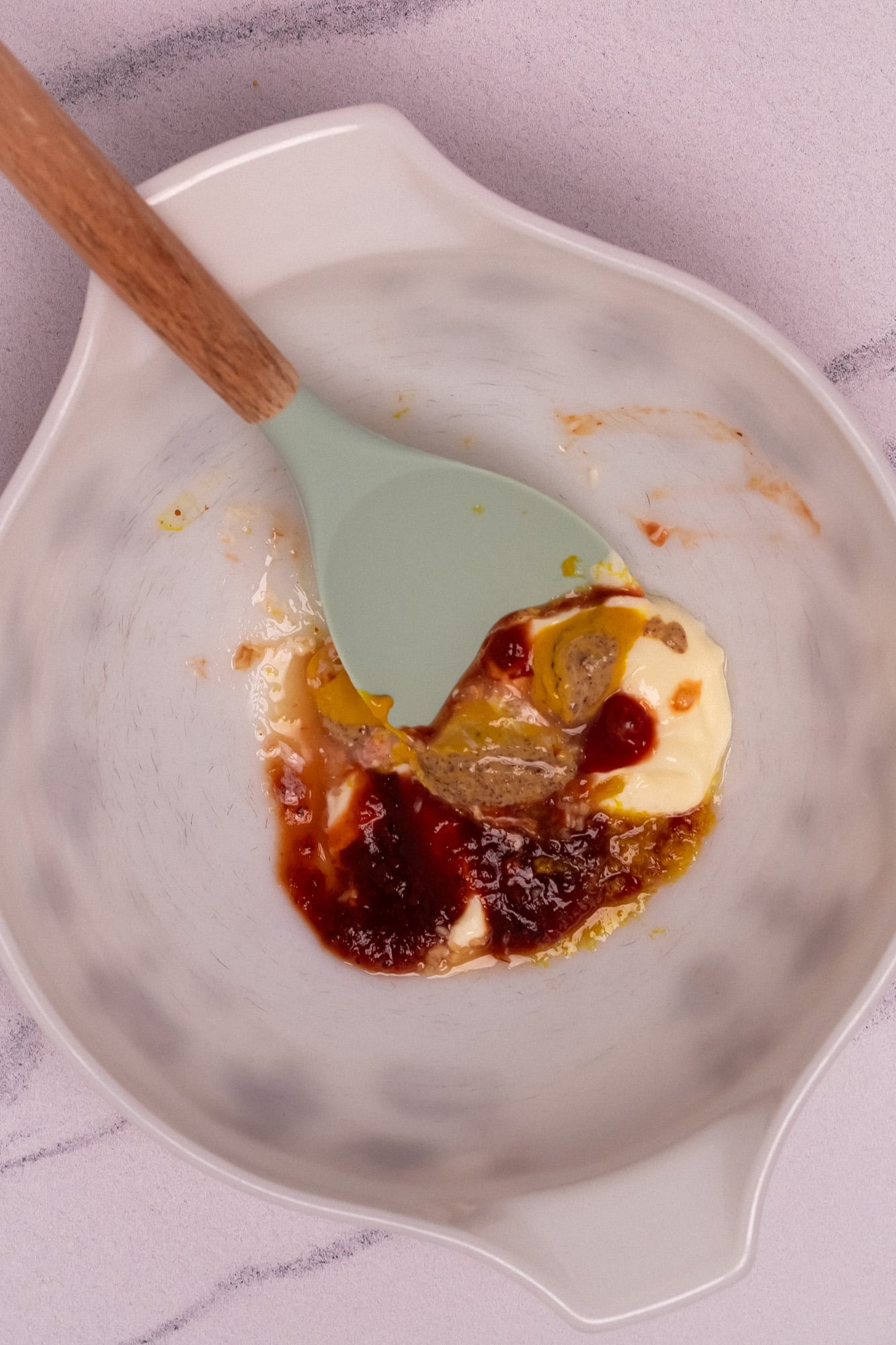Mayo, Creole mustard, yellow mustard, ketchup, chili sauce, and dried spices in a large white mixing bowl.