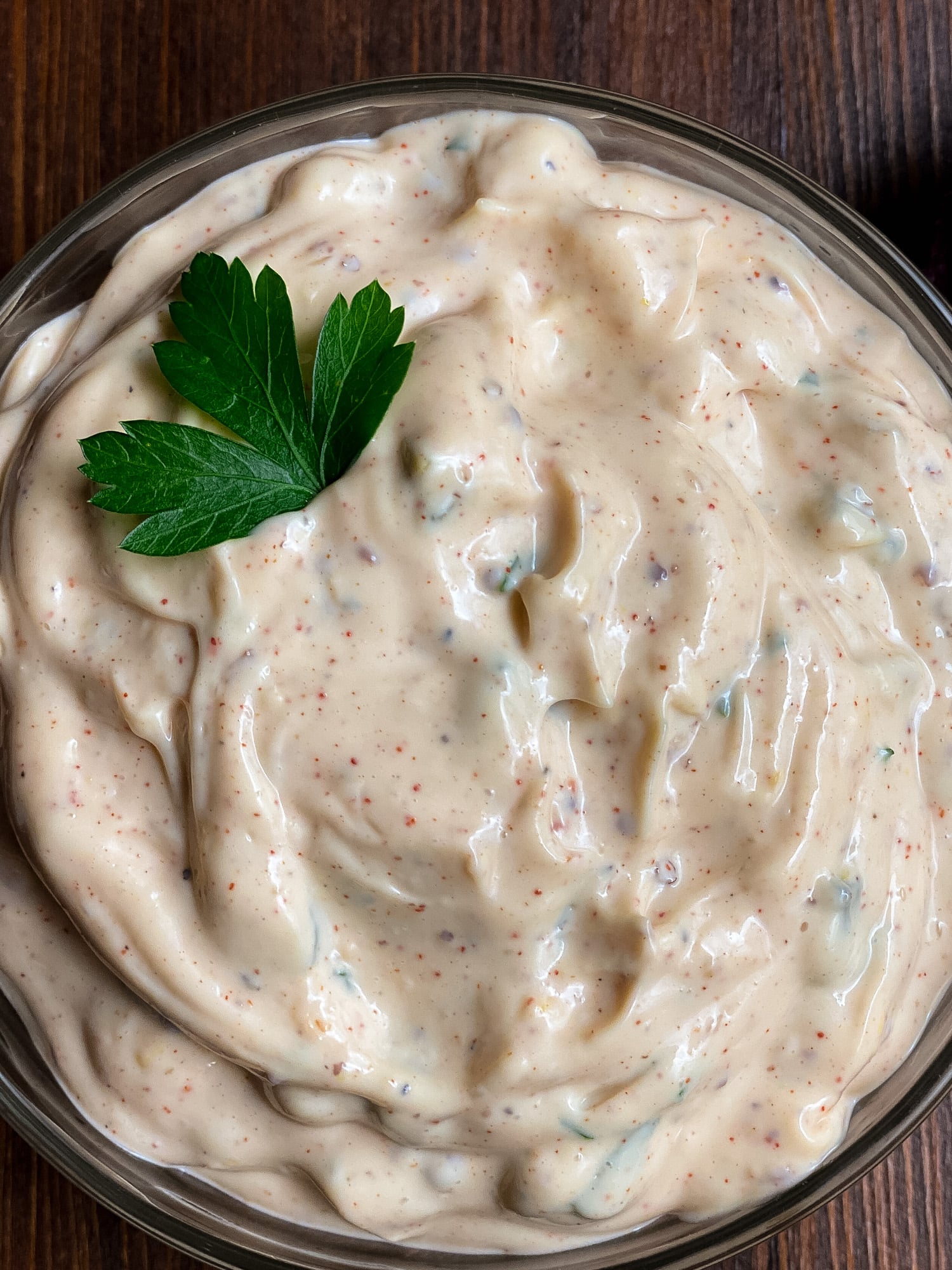 A closeup of Cajun tartar sauce in a clear bowl. 