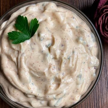 Cajun tartar sauce in a bowl set atop a dark brown background.