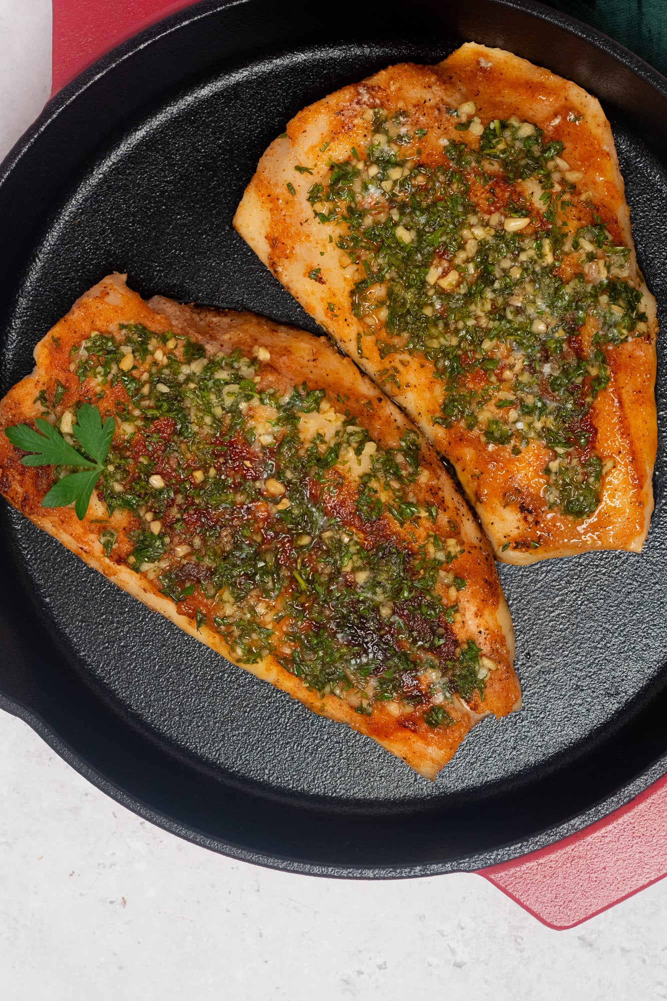 Pan seared snapper in a red enameled cast iron skillet.