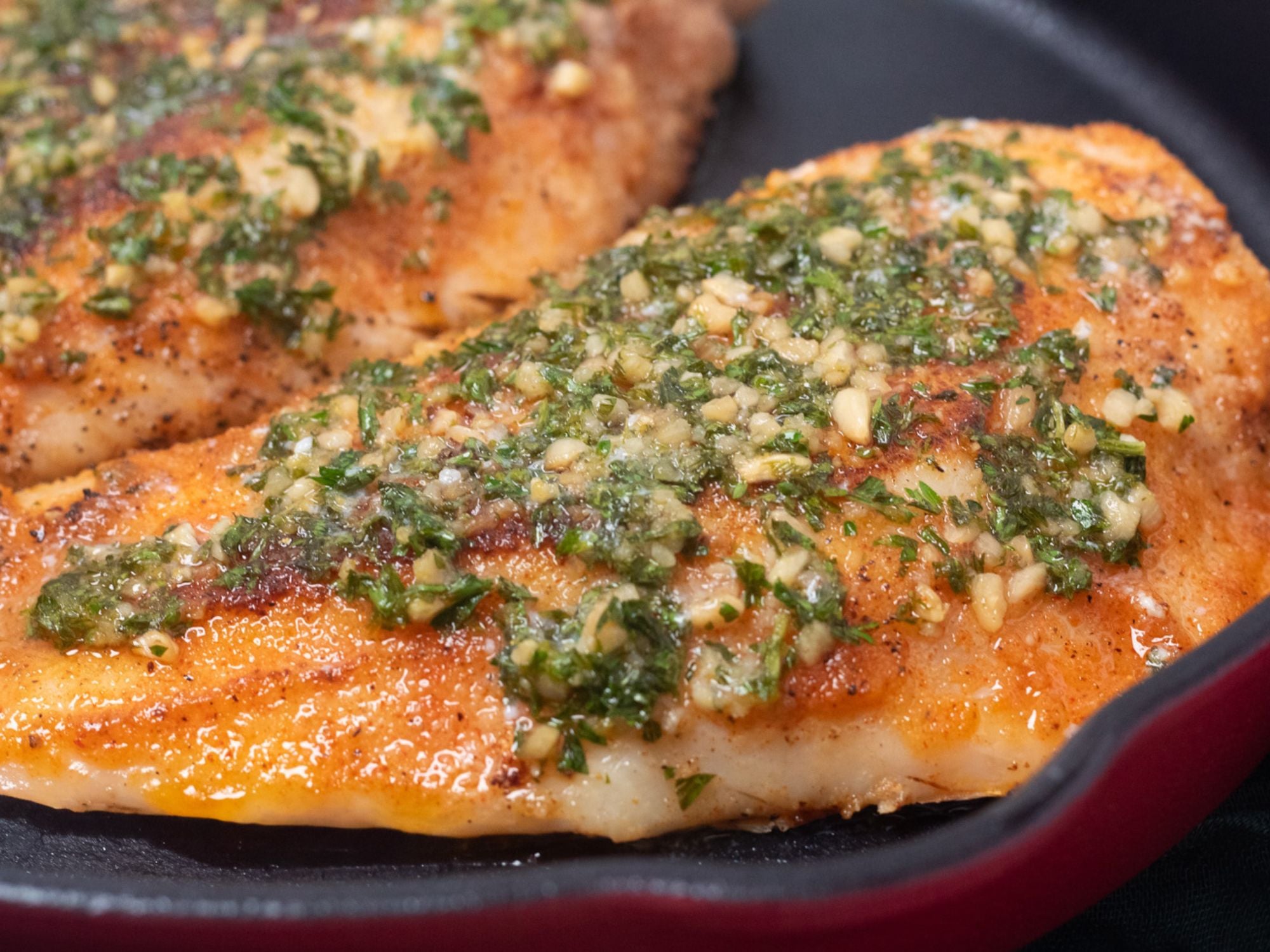 Side image of pan seared snapper in a lemon garlic butter sauce in a pan.