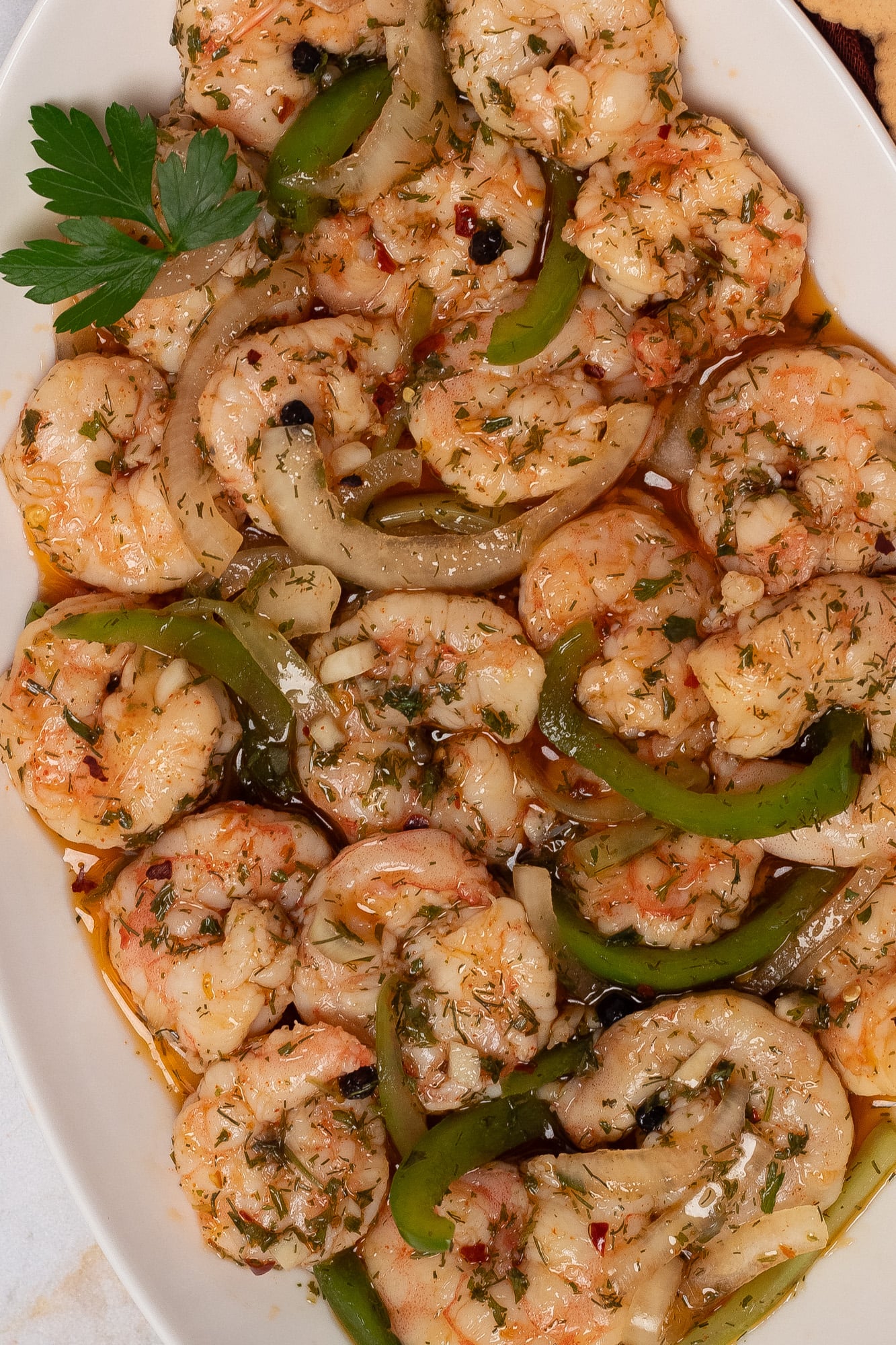 A closeup image of pickled shrimp on a white oblong serving dish.