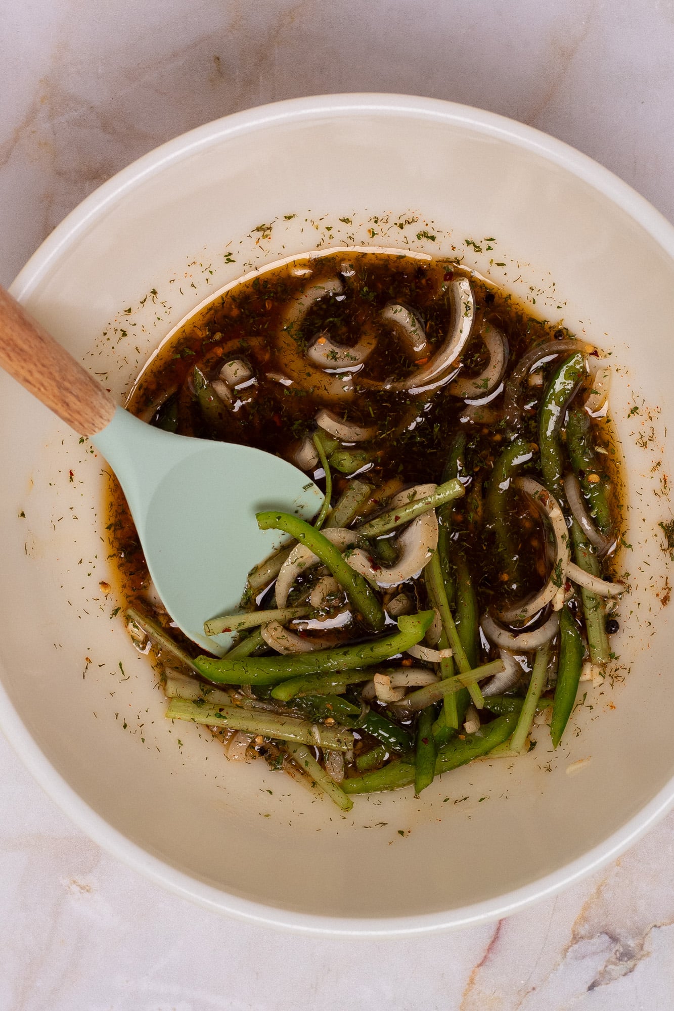The pickling brine for pickled shrimp in a bowl with a light green silicone spatula.