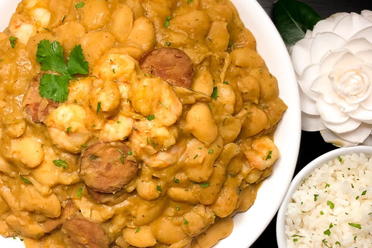 Cajun butter beans with shrimp and sausage on a round white plate.