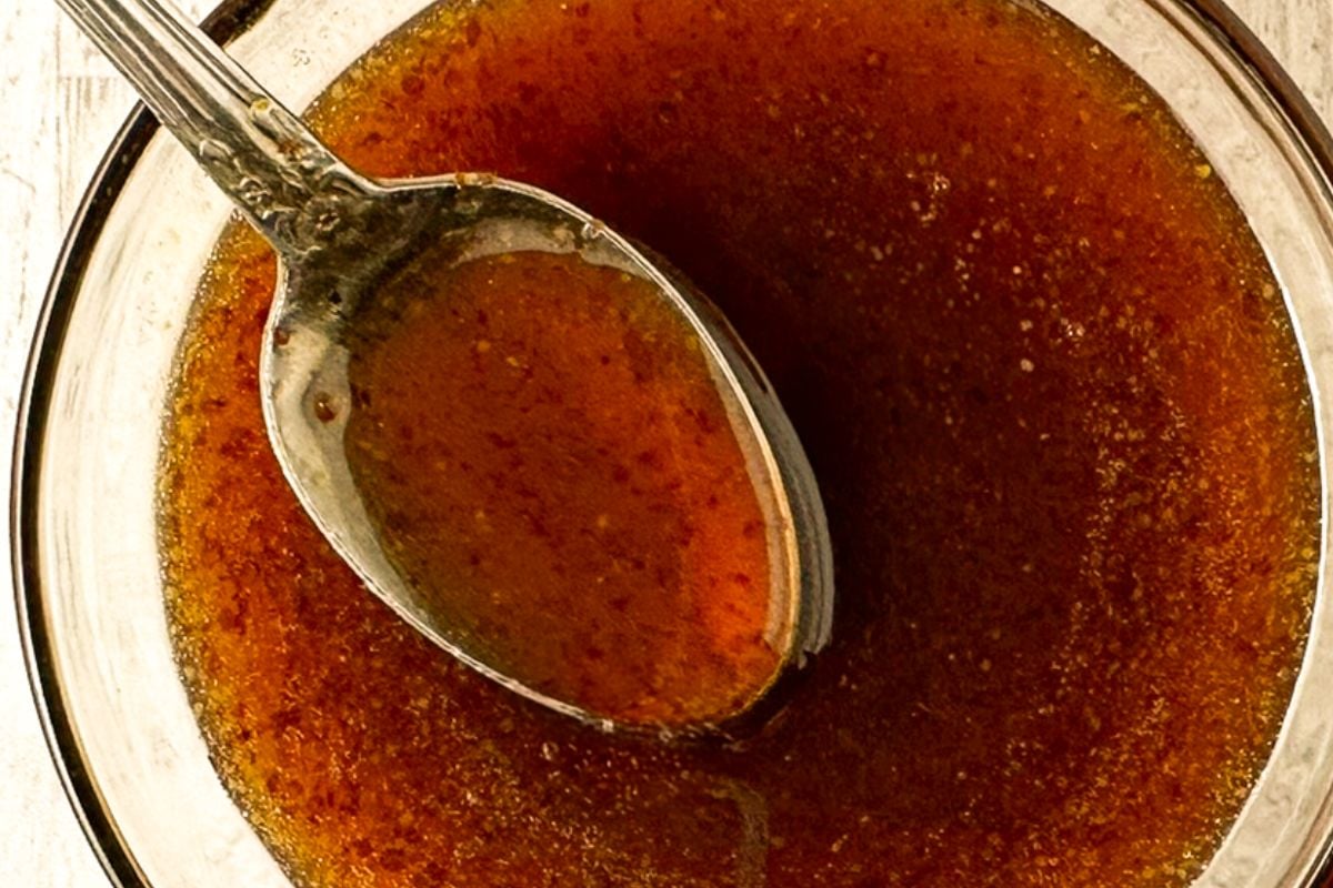 Honey mustard glaze in a clear bowl with a spoon. 