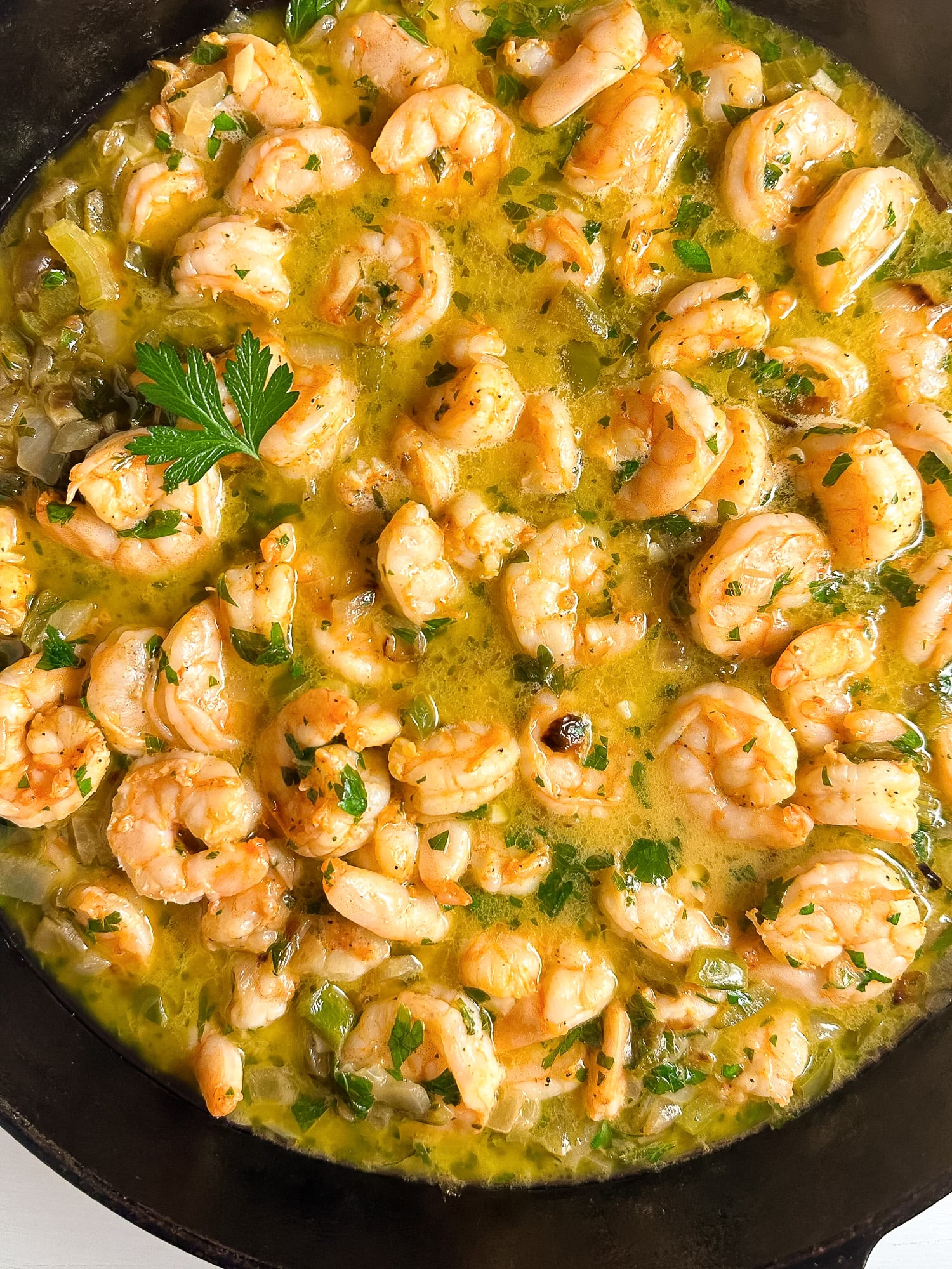 A closeup shot of Cajun shrimp scampi in a black skillet.