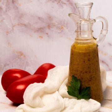 Creole mustard vinaigrette in a clear glass dressing bottle.