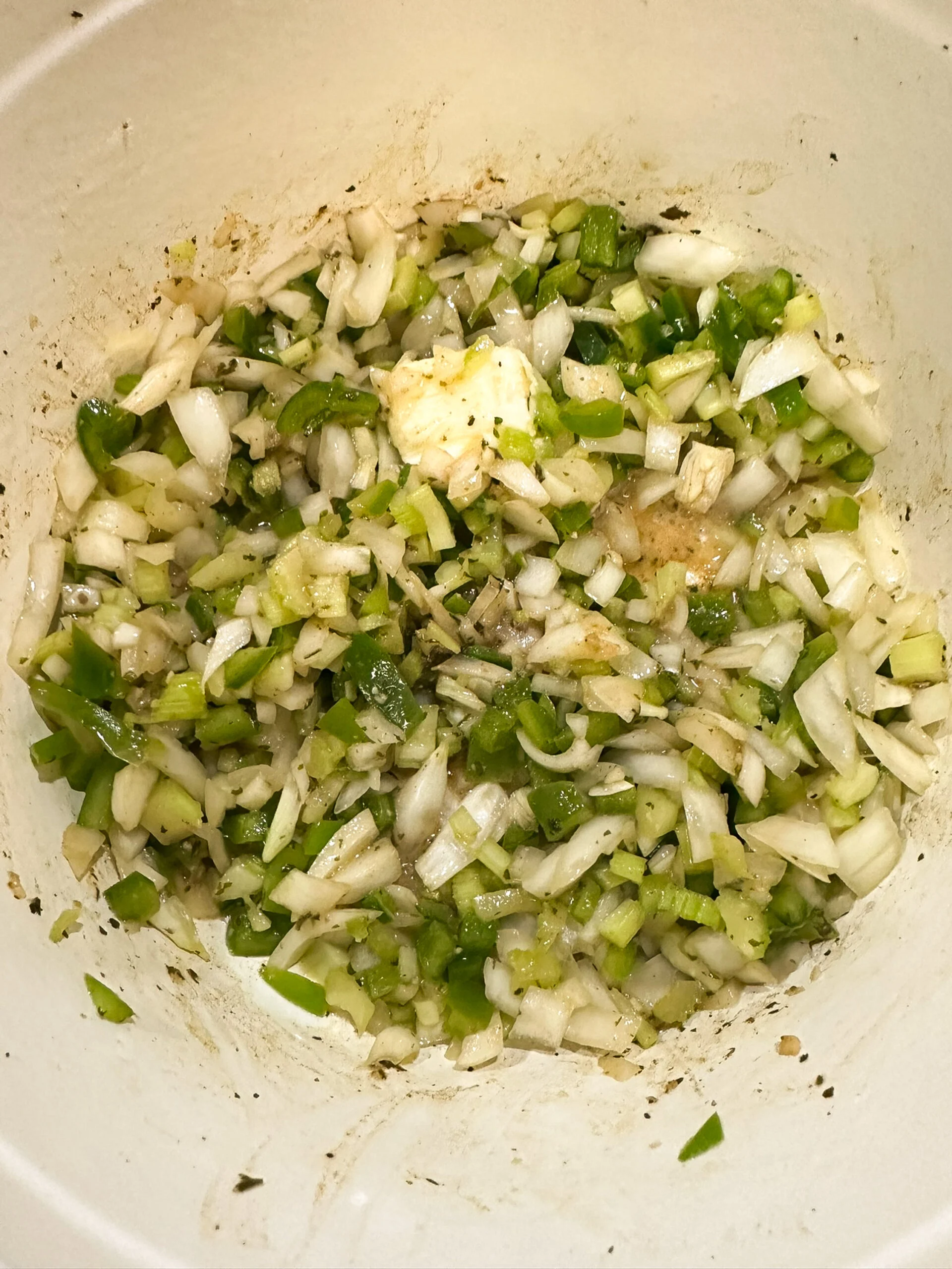 Chopped onion, bell pepper, and celery in a pot with pan drippings and butter.