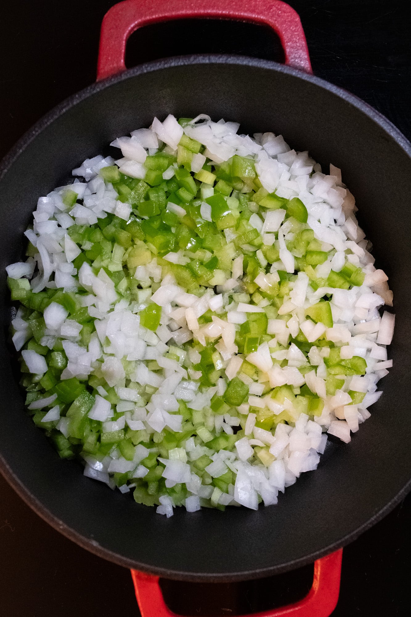 Chopped onion, celery, green bell pepper, high-heat olive oil, and butter in a red pot.